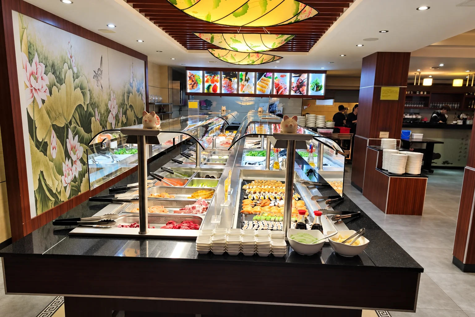 Buffet counter with sushi, small bowls and tongs, a large lotus-flower mural on the left, leaf-shaped ceiling lamps above.