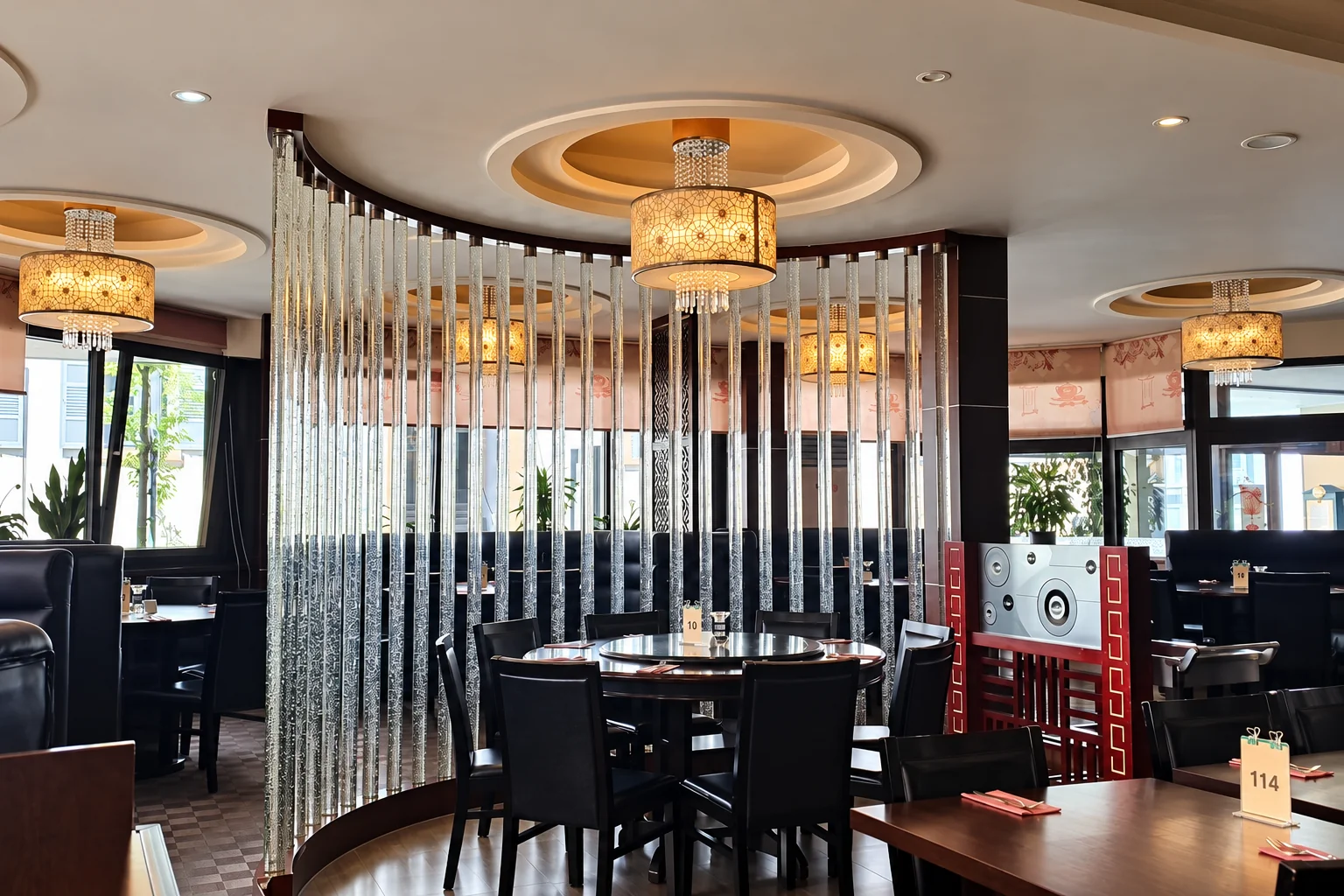 A table with black chairs behind a divider of glass rods, pendant lamps above.