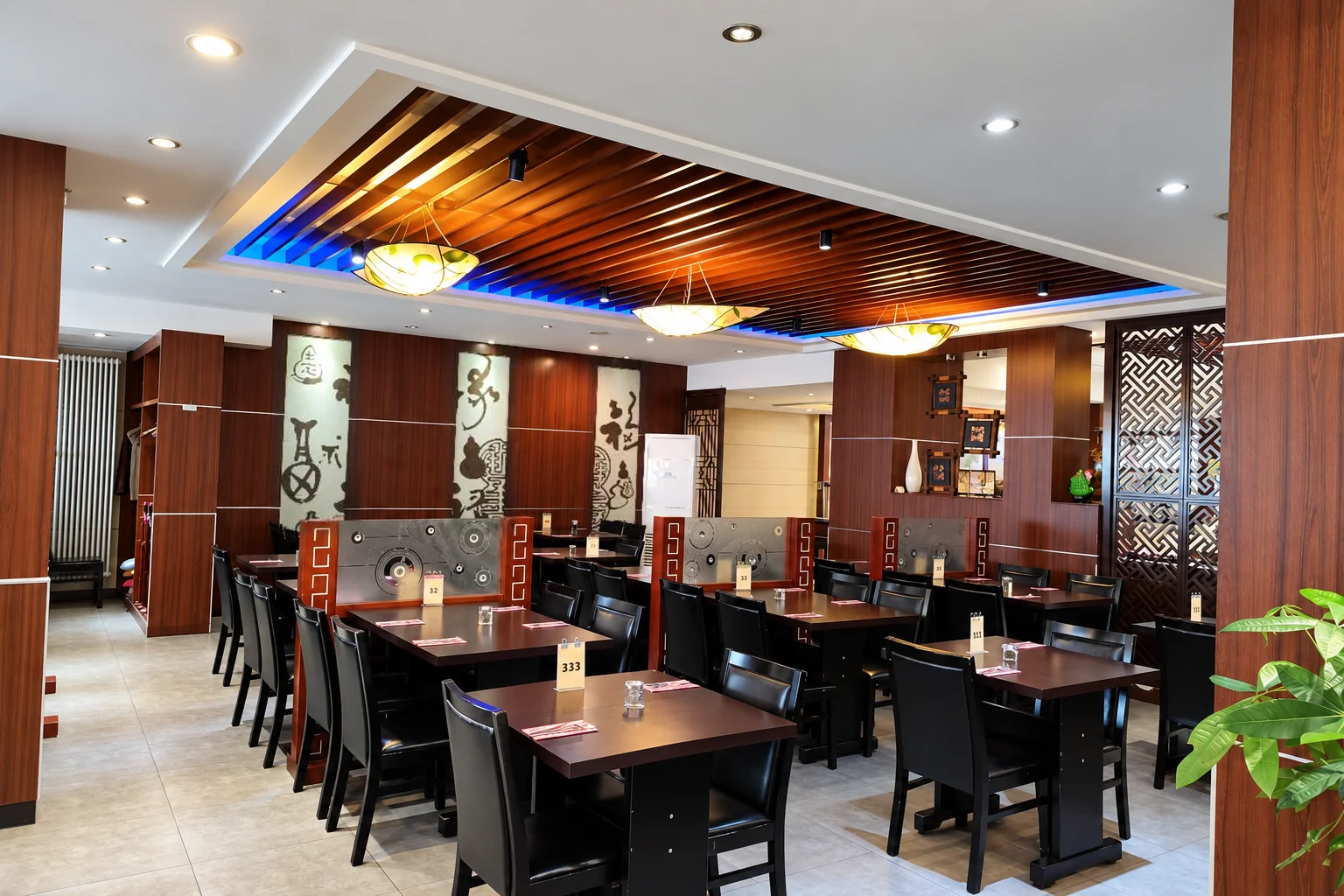 Dining room with dark tables and black chairs, a wooden slatted ceiling with a blue light strip, wall panels with characters.