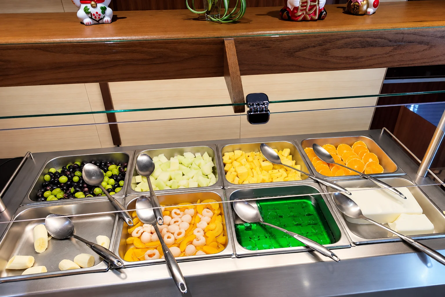 Fruit and green jelly in stainless-steel trays at the buffet, with ladles.